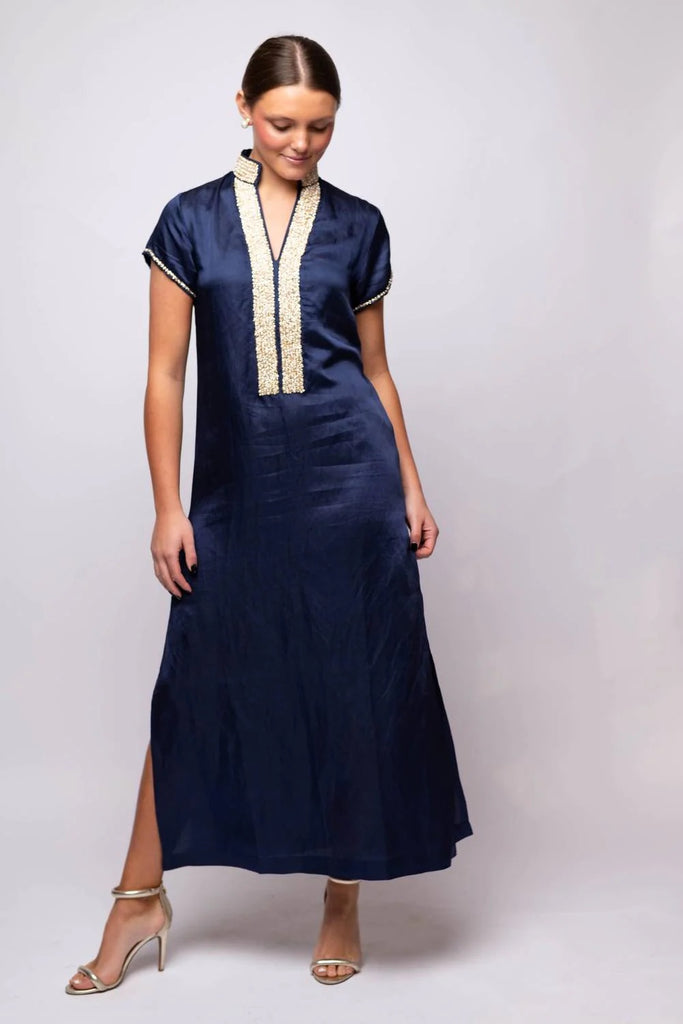 Woman wearing a navy dress with white trim on a plain background