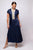 Woman wearing a navy dress with white trim on a plain background
