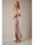 Woman wearing a pink dress with a slit on a plain background