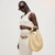 Woman holding a woven bag against a plain background